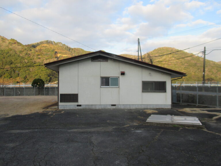 矢原浄水場旧公舎解体撤去工事の解体前の旧公舎外観(山を背景に)